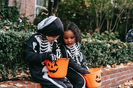 An image of two children dressed in Halloween costumes counting their candy