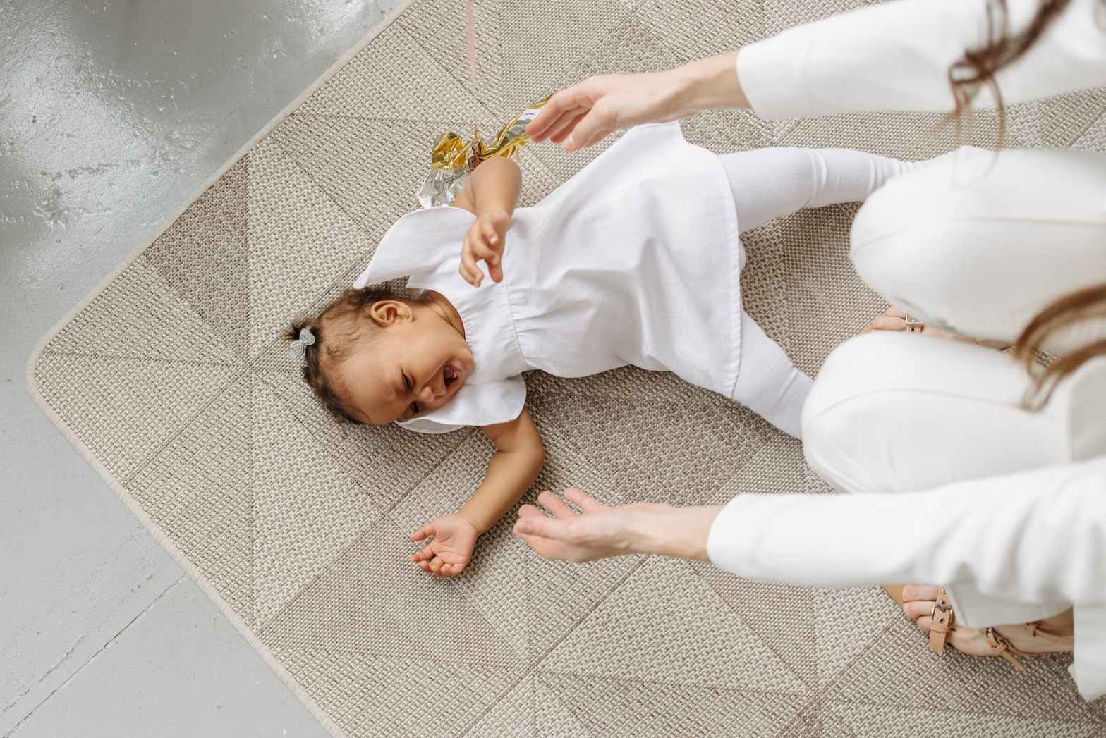 high angle shot of a baby girl crying on the floor